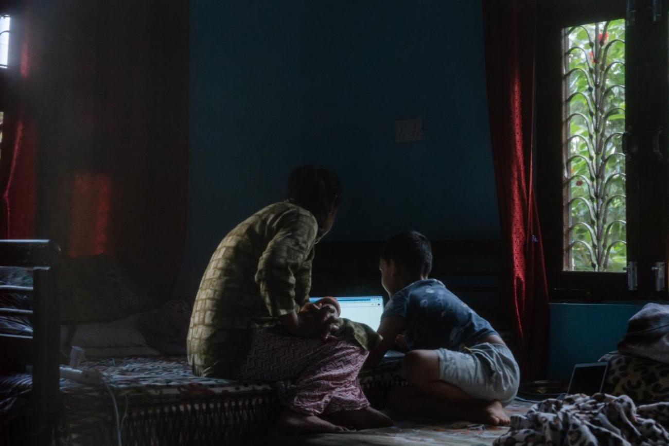 Tika Subedi and her son look at a laptop in their home in Surkhet District in western Nepal.