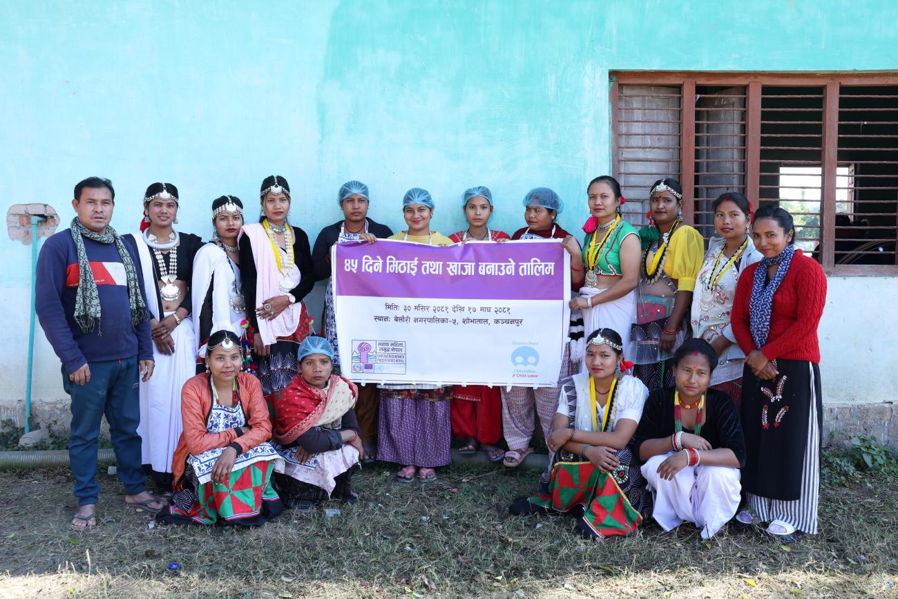 A group of people, some standing and some sitting, holding a rectangular banner that reads "45 Days Sweets and Lunch Making Training."