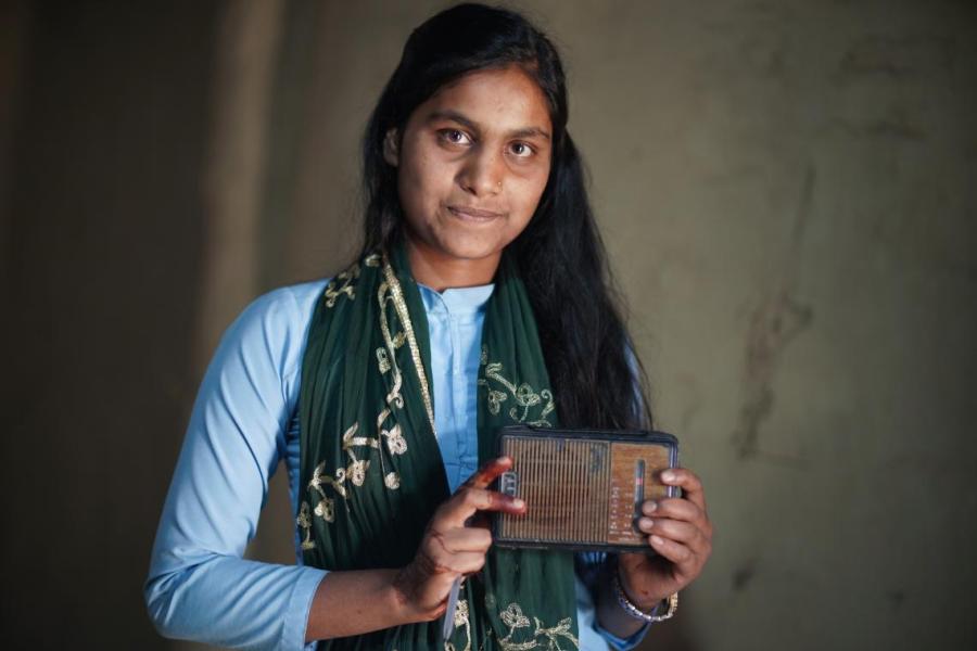 Sakila Khatun, 13, holds up a radio in her home in Parsa District in southern Nepal.