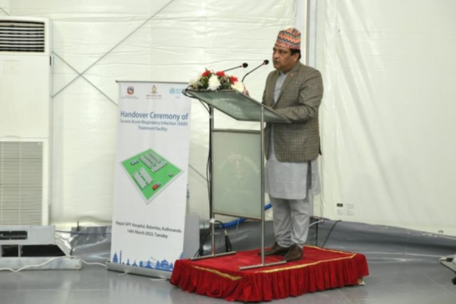 Hon'ble Secretary of the Ministry of Health and Population, Dr. Roshan stands on the podium on stage and gives his speech. Pokhrel, providing his remarks at the handover of the Severe Acute Respiratory Infections Treatment Facility in Nepal.