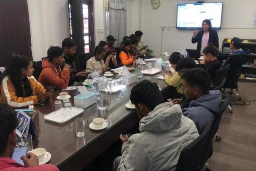 Rina gives presentation to around nineteen youth participants sitting in front of her and a tv screen at her back.  Rina Pradhan (standing far right), national UN Volunteer Programme Assistant with UNV engages the youth from Surkhet, Karnali province on becoming a UN Volunteer. ©UNV, 2022
