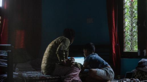 Tika Subedi and her son look at a laptop in their home in Surkhet District in western Nepal.