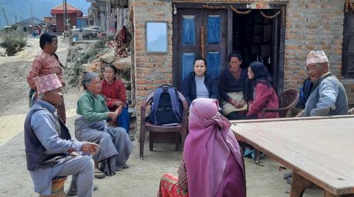 A group of around nine people sit outside a newly constructed house and have a discussion.  Assessment for persons with severe mental health condition at Lele, Godawari, Province Bagmati, Nepal; Photo Credit: KOSHISH