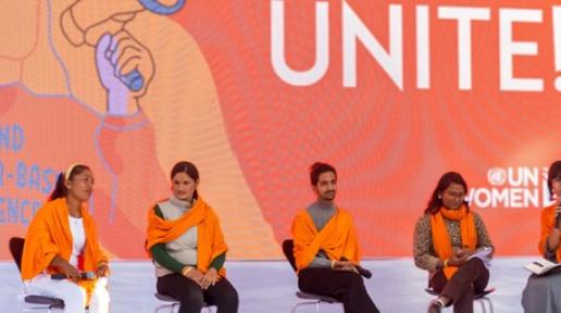 Five filmmakers are sitting in a chair on stage with an orange scarf around them